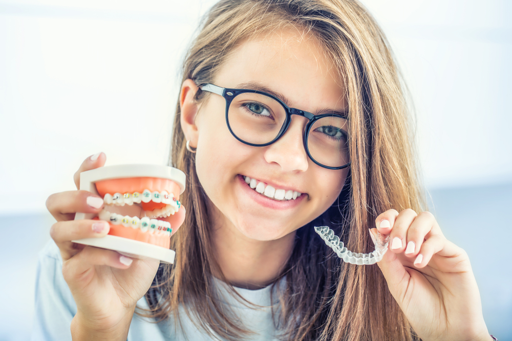 Lady holding up braces and Invisalign